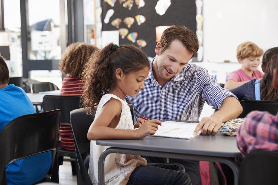 22555390-teacher-working-with-young-schoolgirl-at-her-desk-in-class.jpg